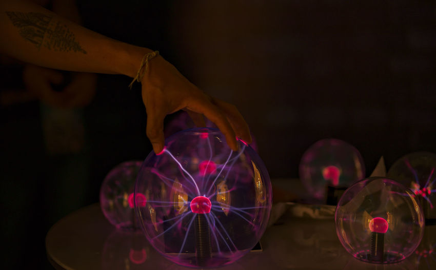 Close-up of hand holding plasma ball on table