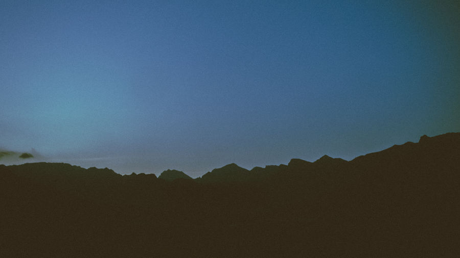 Silhouette of mountain range against clear blue sky