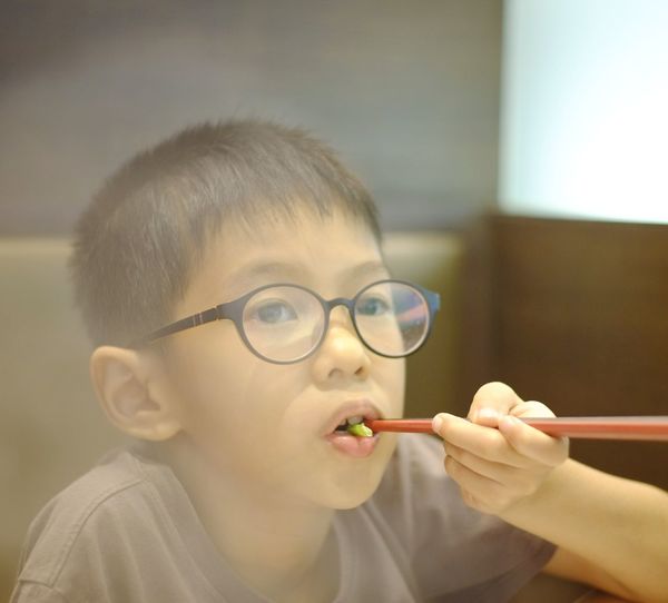 Boy eating food while looking away at home