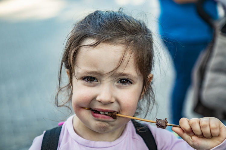 Close-up portrait of girl eating food outdoors