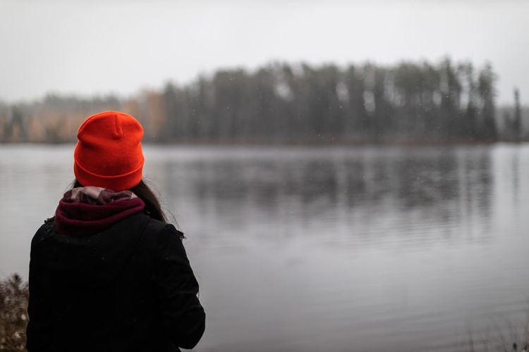 Woman in orange toque looking out on lake.