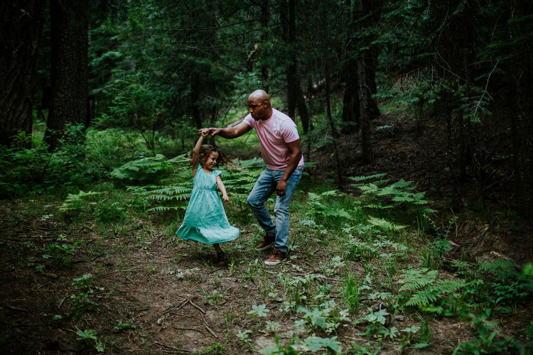 Father and daughter dancing in the middle of the forest