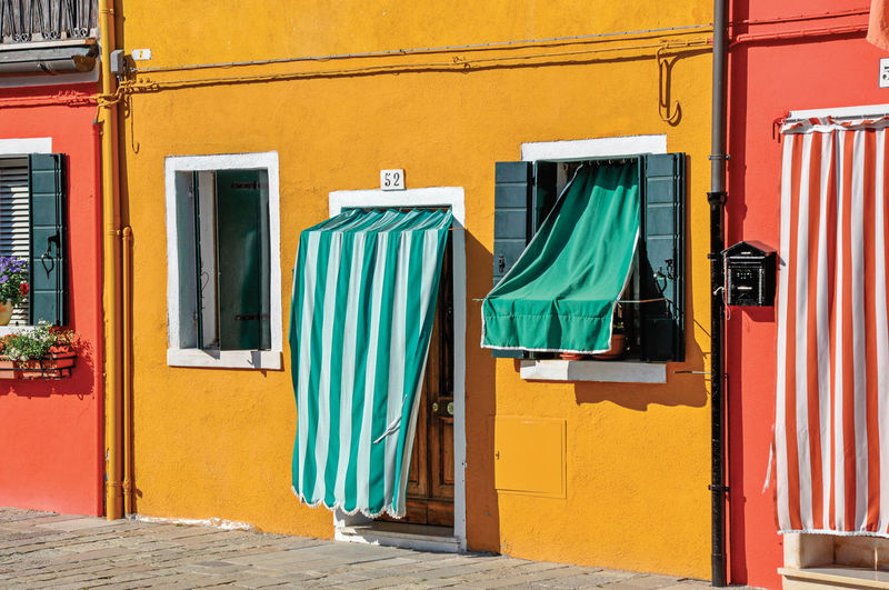 Colorful houses and doors with curtain in burano, a little town full of canals near venice, italy.