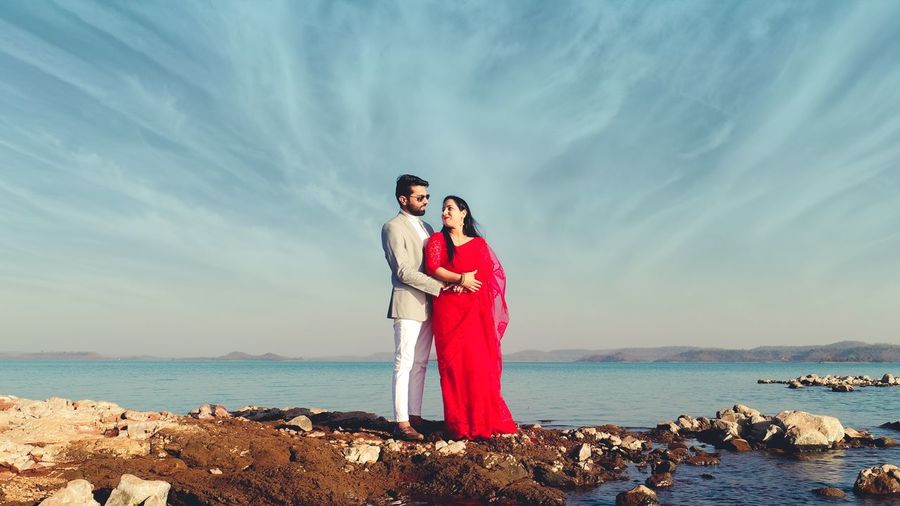Rear view of couple standing at sea against sky