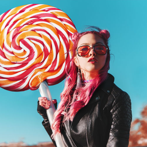 Portrait of beautiful woman holding artificial lollipop