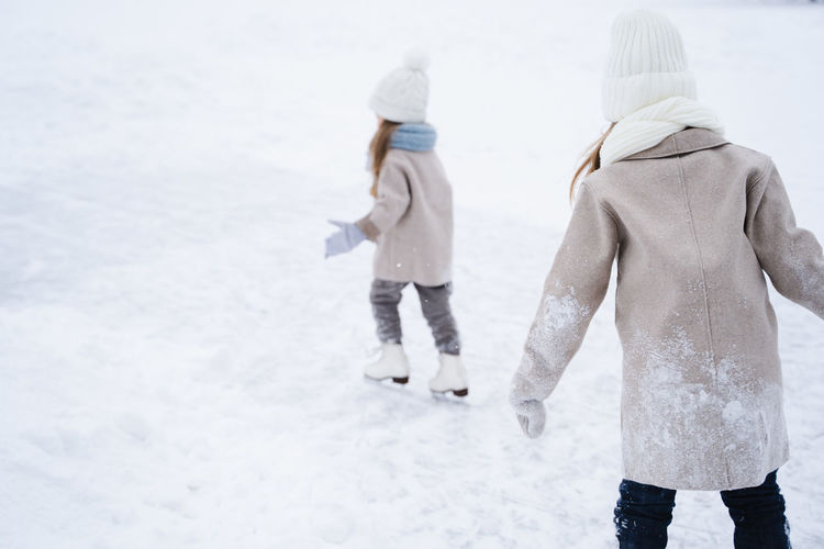 Cute sisters playing on snow covered land during winter