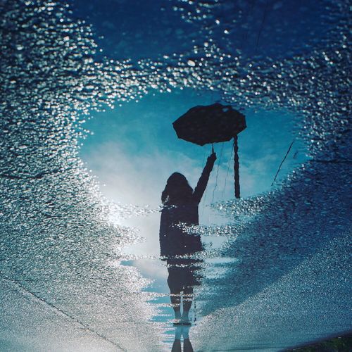 Reflection of person holding umbrella