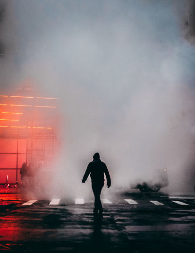 Silhouette man standing on street in city