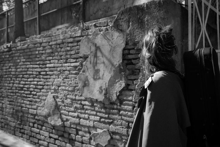 Rear view of woman standing on brick wall