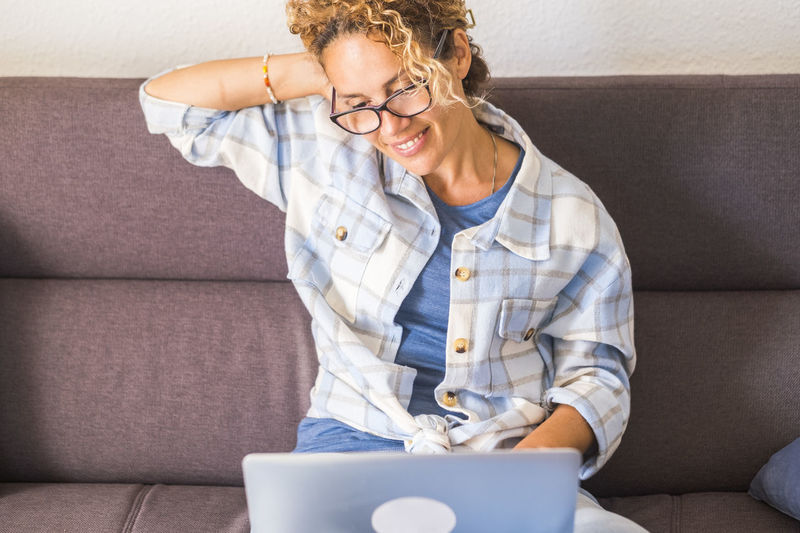 Young woman using digital tablet while sitting on sofa at home