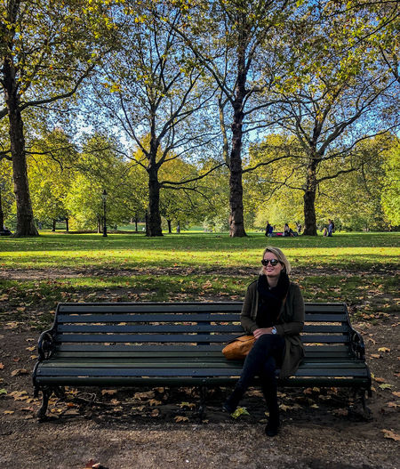 Rear view of woman sitting on bench in park during autumn