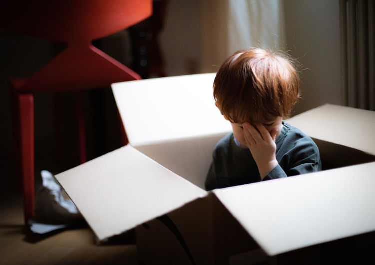 Cute boy sitting in cardboard box