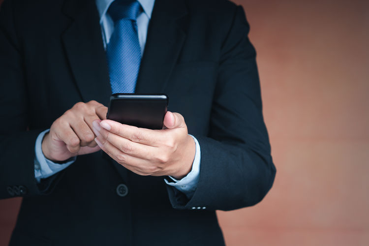 Midsection of businessman using mobile phone