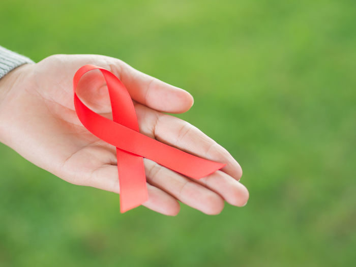 Cropped hand of woman holding aids awareness ribbon