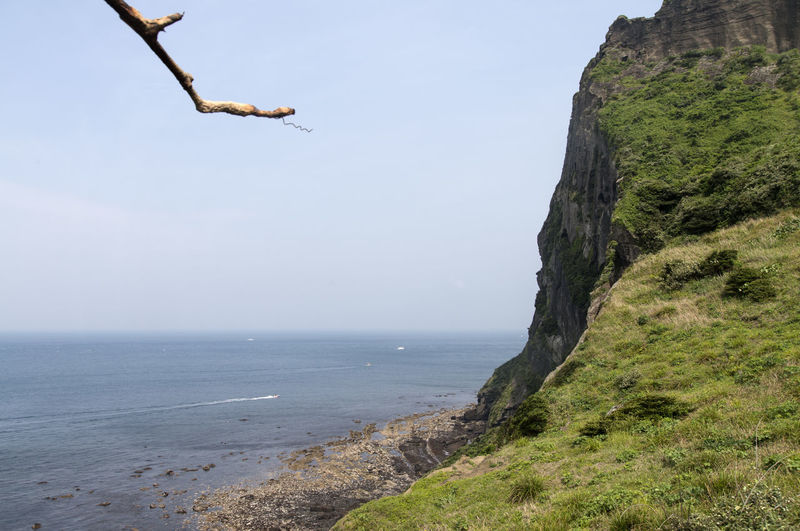 Scenic view of mountain by sea against sky on seongsan ilchulbong at jeju island