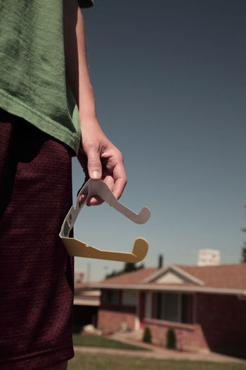 Midsection of man holding glasses against clear sky