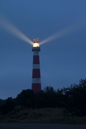 Low angle view of lighthouse by building against sky