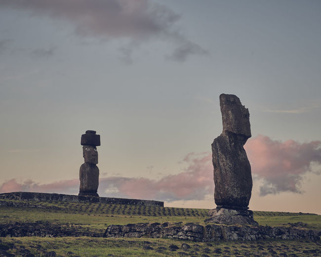 Moai statues on field against sky during sunset on rapa nui
