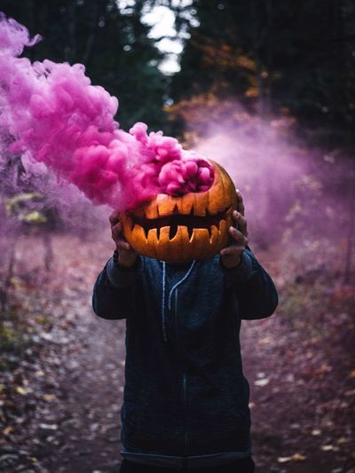 Person holding pumpkin emitting purple distress flare
