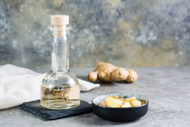 Ginger serum in a bottle and chopped ginger in a bowl on the table. alternative natural cosmetology
