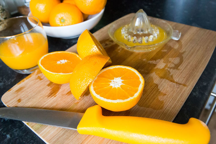 Close-up of orange juice by slices and knife on cutting board