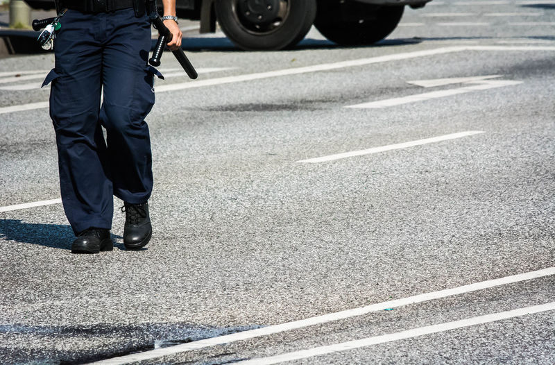 Low section of police officer walking on street