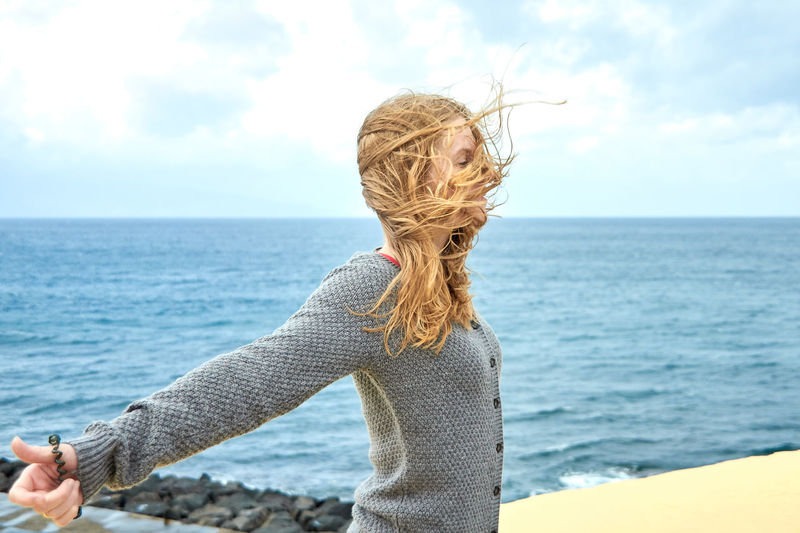 Woman with long hair standing against sea