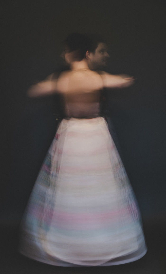 Blurred motion of woman spinning against black background