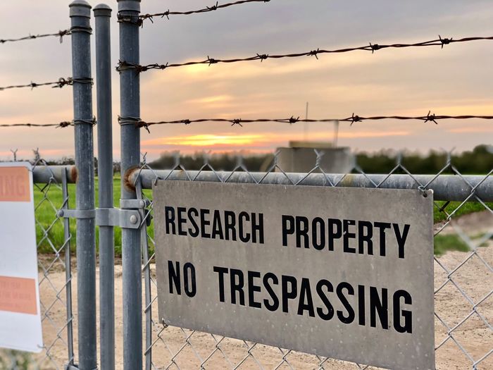 Close-up of no trespassing sign on fence against sky during sunset