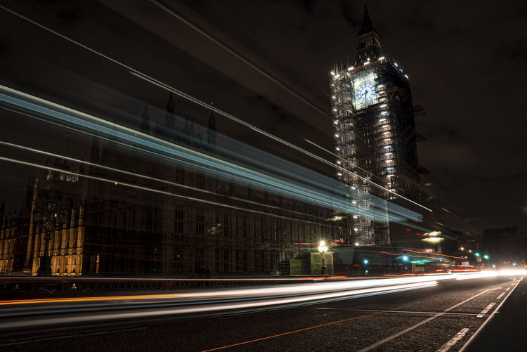 The palace of westminster and illuminated big ben at night with light trail