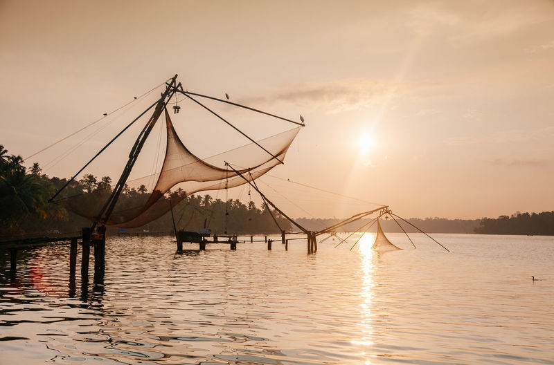 Fishing net in lake against sky during sunset
