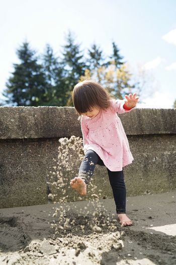 View of young girl kicking sand