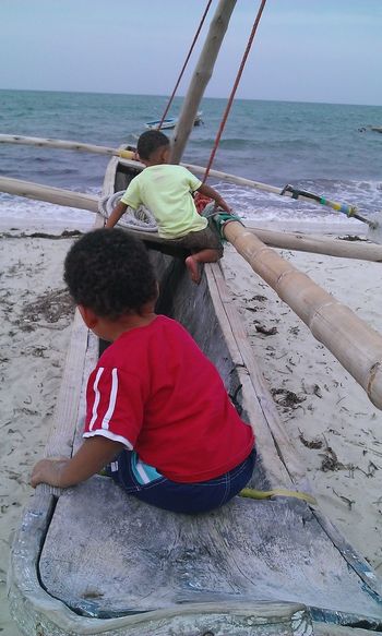 Boys sitting in dhow boat at beach