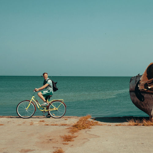Side view of man riding bicycle against sea