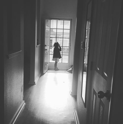 Mid distant view of girl standing by entrance door at home