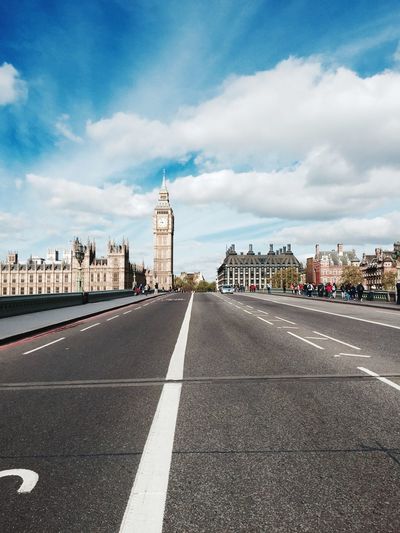 Road leading towards big ben against cloudy sky