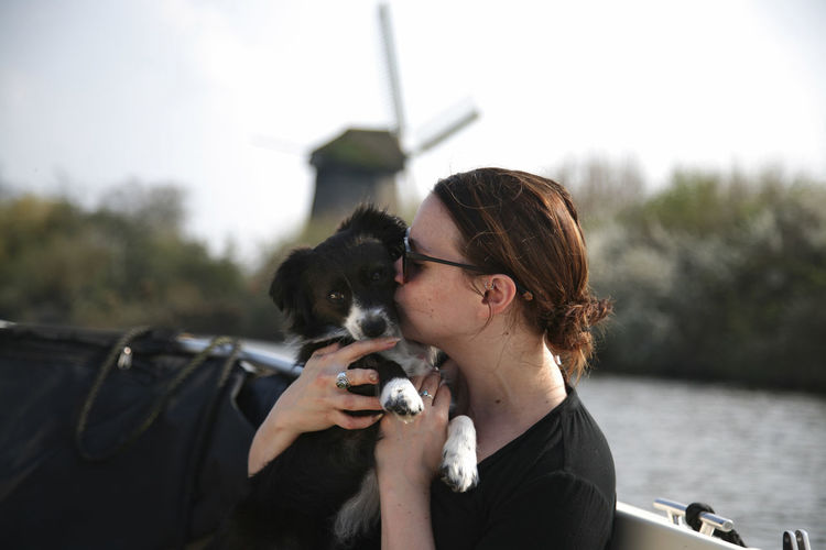 A young woman kissing her small puppy on a boat in holland.
