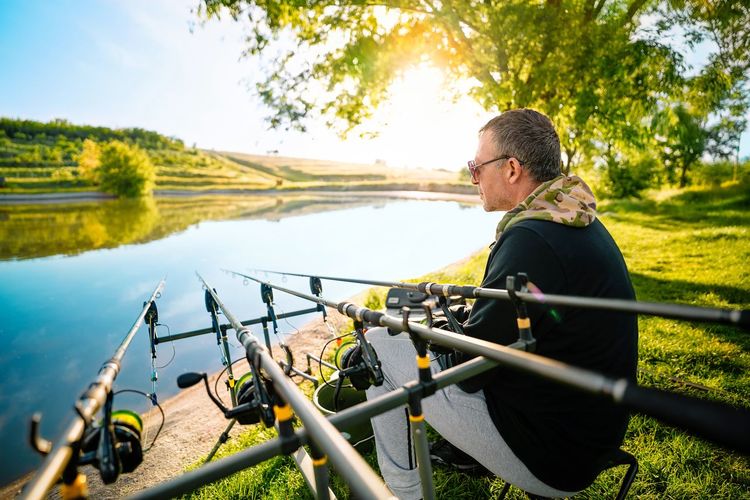 Fisherman by fishing reels on the lake shore