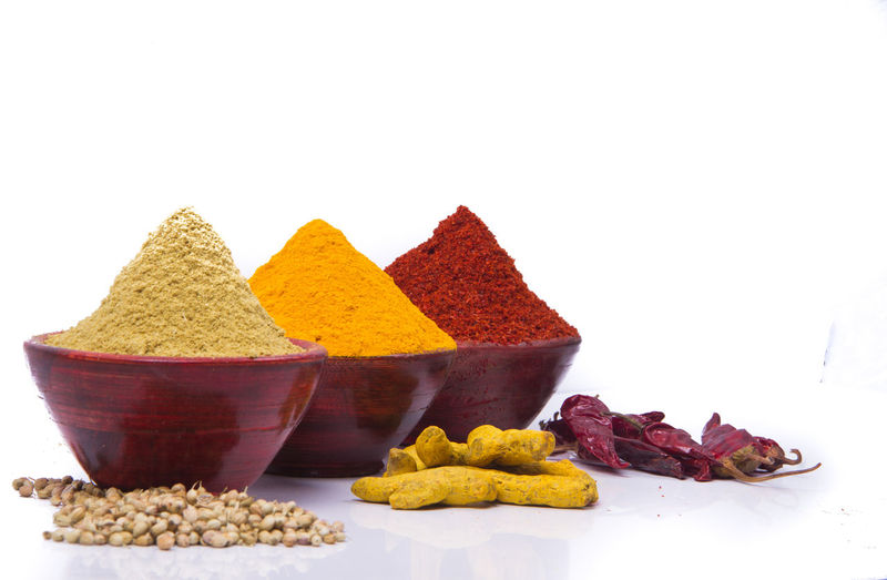Close-up of various spices in bowls on white background
