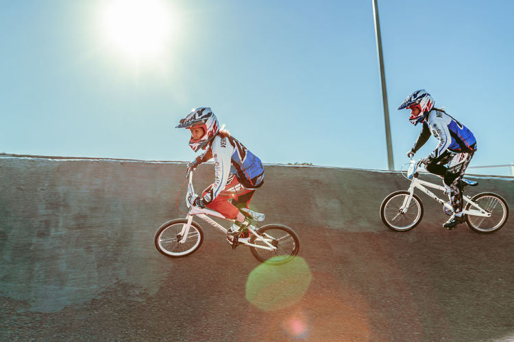 Side view of people riding bicycled on sunny day