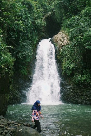 Woman exploring in river amidst trees in forest