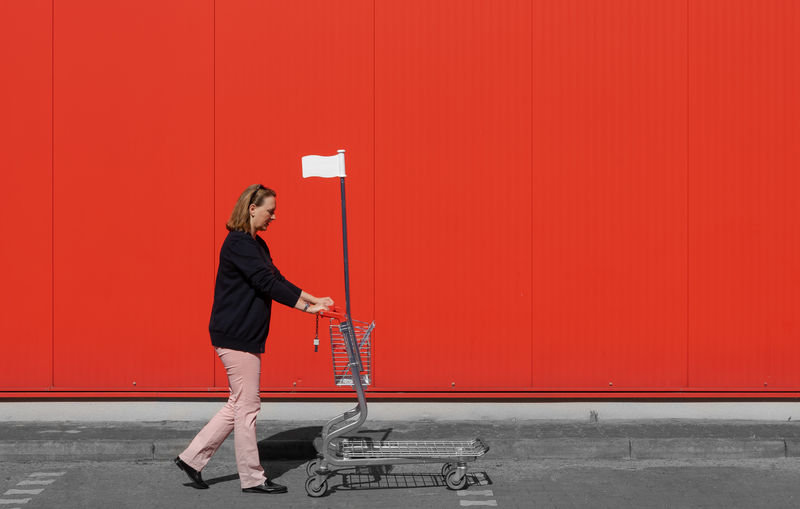 Woman with shopping cart against red wall