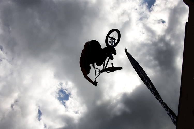 Silhouette of person jumping with bicycle