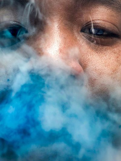 Close-up portrait of man amidst blue smoke