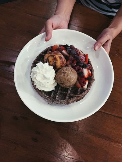 Cropped hands of woman holding ice cream in plate