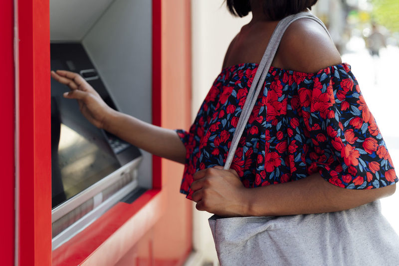 Woman with shoulder bag using atm