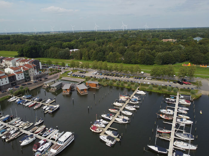High angle view of sailboats moored at harbor against sky