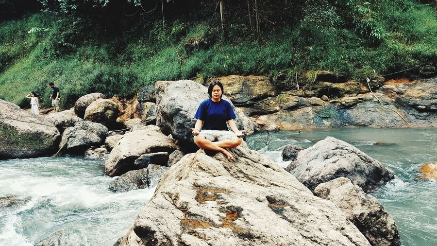 Woman doing yoga on rock at riverbank