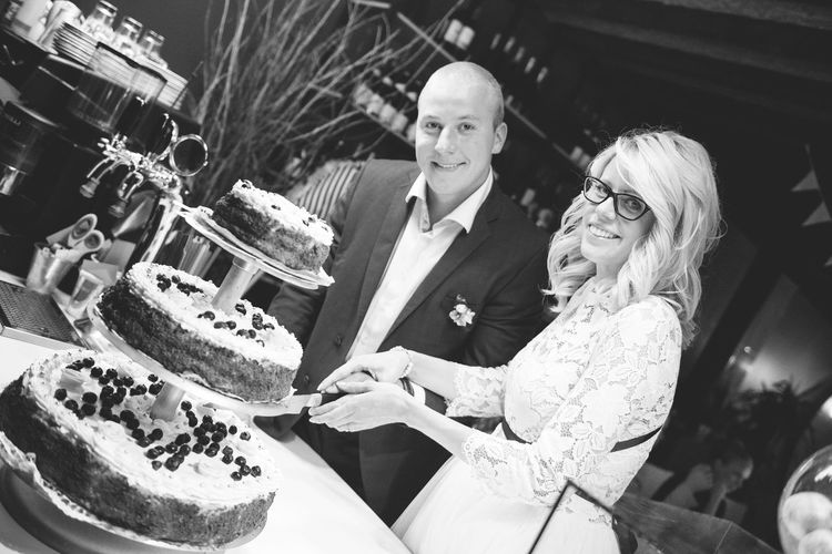 Tilt portrait of newlywed young couple cutting cake during wedding reception