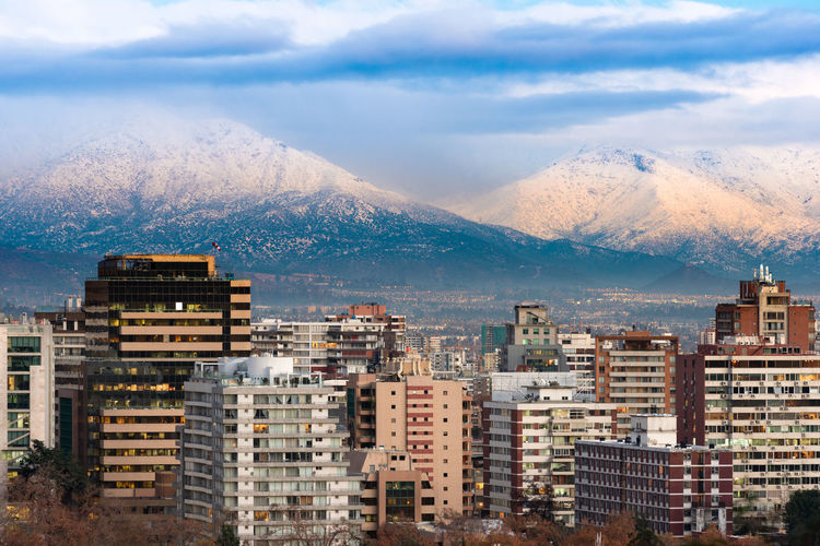 Buildings in city against mountains during winter